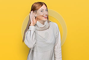 Young irish woman wearing casual winter sweater smiling with hand over ear listening an hearing to rumor or gossip