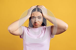 Young, irritated girl grabbing head.