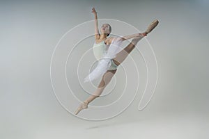 young Japanese ballerina in a photo studio does a grand jete splits in a jump