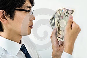 Young Japanese businessman counting money. Holding a stack of Japanese yen banknotes.