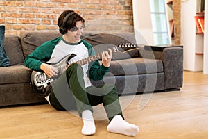 Young Japanese Musician Guy Practicing Electric Guitar In Living Room