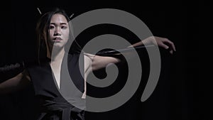 Young japanese woman with katana on black background