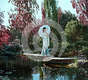 A young Japanese woman with long, black hair adorned with Kandzashi, flowers and long hairpins with crystal beads walks