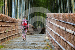 Young Japanese woman in a traditional Kimono dress strolls by the Bamboo Grove at Adashino Nenbutsuji Temple in Kyoto, Japan