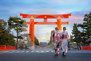 Young Japanese woman in traditional Yukata dress stroll by the gigantic great torii gate of Heian Jingu shrine in Kyoto, Japan