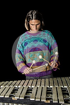 Young jazz musician playing the vibraphone in his private rehearsal room. Black background. photo