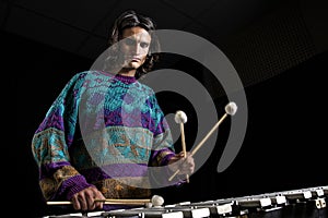 Young jazz musician playing the vibraphone in his private rehearsal room. Black background. photo