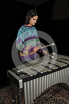 Young jazz musician playing the vibraphone in his private rehearsal room. Black background. photo