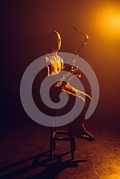 young jazzman looking at camera while sitting on stool