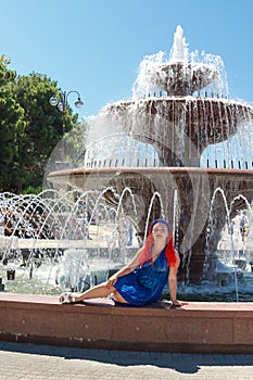 A young Jewess with African pigtails sits on the background of a fountain.