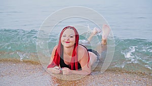 A young Jewess with pigtails of red color on vacation lies on the seashore.