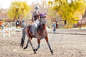 Young jockey girl riding horse on competition