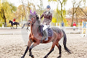 Young jockey girl riding horse on competition