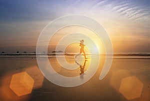 Young jogger girl running through the surf at amazing sunset.