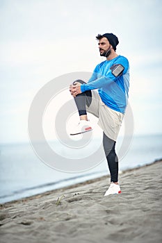 Young jogger worming up for jogging on the beach photo