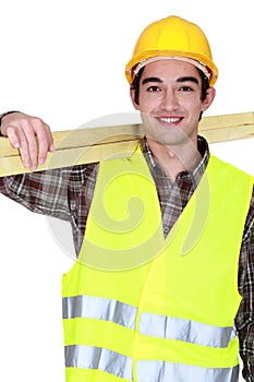 Young joiner carrying planks