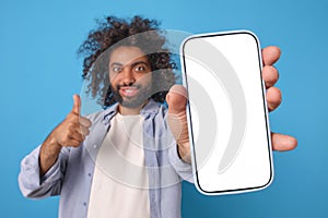 Young joy optimistic Arabian man with smartphone in hand showing thumbs up