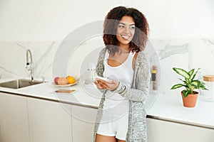 Young joyful afro american woman holding mobile phone