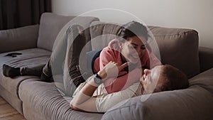 Young joyful couple relaxing, embrace and have fun lying on the sofa in the living room with loft interior. Having fun