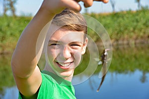 Young joyful guy shows his catch on a fishing trip