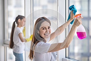 Young joyful mother with daughter doing cleaning.