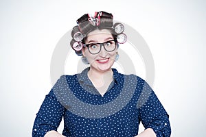 Young joyful positive smiling girl in glasses and hair curlers on her head.