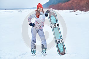 Young joyful snowboarder woman smiling and posing