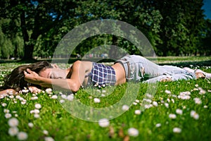 Young joyful woman lies on green grass