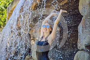 Young joyful woman under the water stream, pool, day spa, hot springs