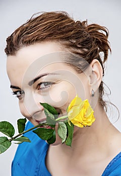 Young joyful woman with the yellow rose in the teeth, holiday th