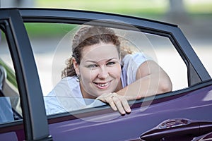 Young joyous beauty woman looking at opened car window