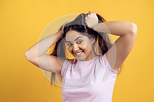 Young joyous girl ruffles long hair on head.