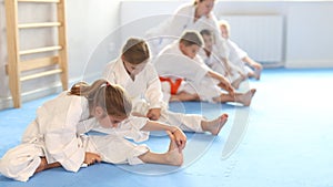 Young karate students engage in stretching exercises to improve their flexibility and balance.