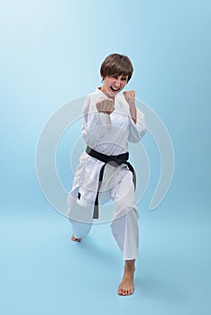 Young karate woman in a white kimono with black belt demonstrates fighting stances and strikes.
