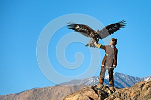 Young kazakh eagle hunter with his golden eagle