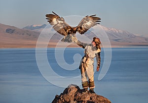 Young kazakh eagle hunter with his golden eagle