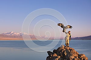 Young kazakh eagle hunter with his golden eagle