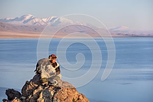 Young kazakh eagle hunter with his golden eagle