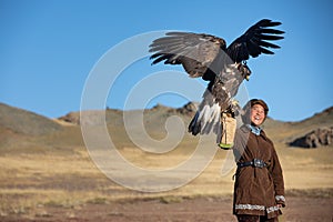 Young kazakh eagle hunter with his golden eagle