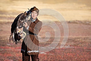 Young kazakh eagle hunter with his golden eagle