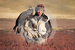 Young kazakh eagle hunter with his golden eagle