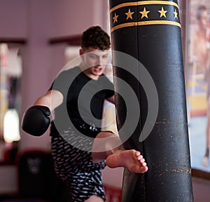 Young kickboxer hitting the heavy bag