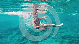 Young kid dives and dances in the sea. 7 year old kid swimming and having fun in summer sea.