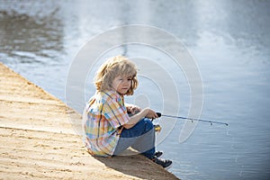 Young kid fisher. Child fishing at river bank, summer outdoor leisure activity. Little boy angling at river bank with