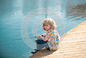 Young kid fisher. Child fishing at river bank, summer outdoor leisure activity. Little boy angling at river bank with