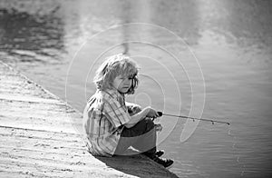 Young kid fisher. Child fishing at river bank, summer outdoor leisure activity. Little boy angling at river bank with