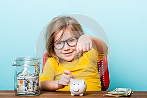 Young kid girl putting money into a piggy bank. Child and money. How to save. Financial education for children