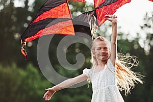 Young kid. Happy girl in white clothes have fun with kite in the field. Beautiful nature