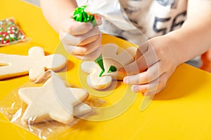 Young kid making cookies at home over yellow table