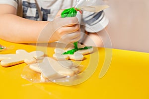 Young kid making cookies at home over yellow table